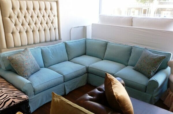 Low Camel Arm Sectional in a Washable White Denim Slipcover, decorated with sky blue accent pillows.